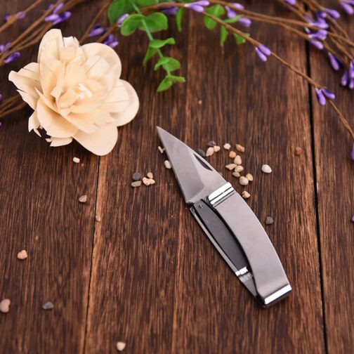 EDC Taschenmesser mit Clip auf Holztisch mit Blume
